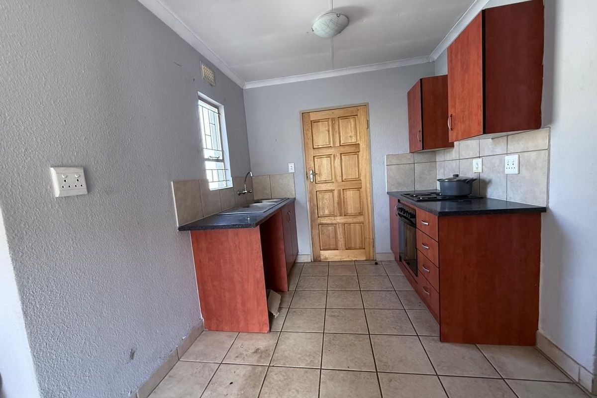 A functional kitchen featuring built-in cabinetry, laminate countertops, a built-in oven and hob, tiled flooring, and a tiled backsplash.
