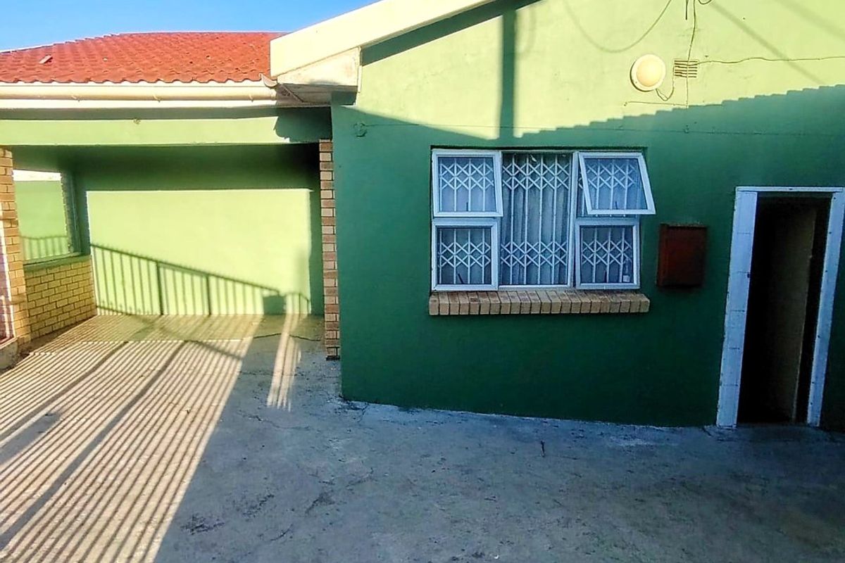 Rear exterior view of the house featuring a concrete patio area, security-fitted windows, and a tiled roof.