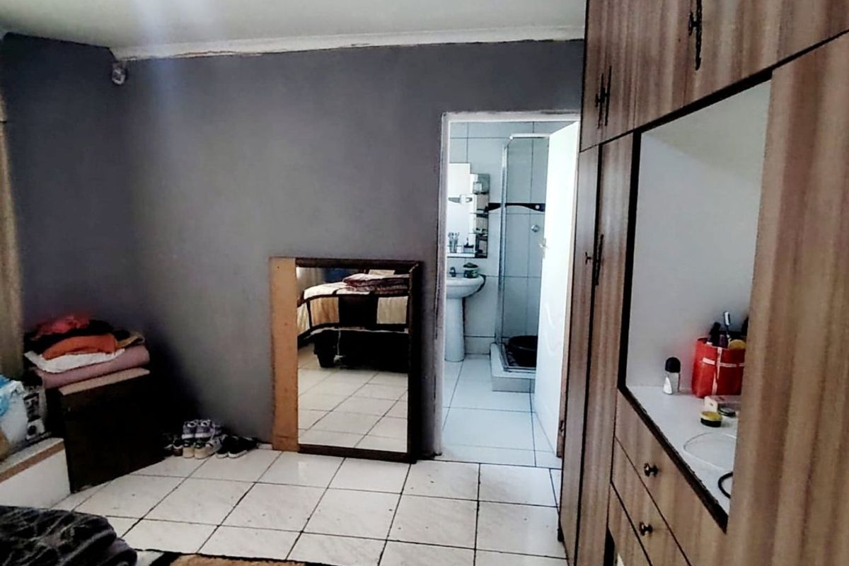 Bedroom featuring built-in cupboards and tiled flooring, with direct access to an en-suite bathroom.