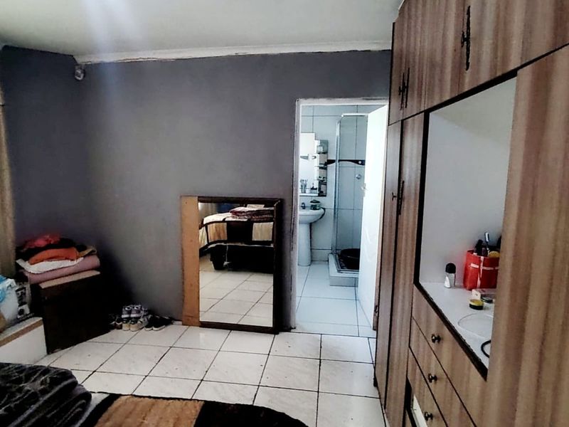 Bedroom featuring built-in cupboards and tiled flooring, with direct access to an en-suite bathroom.