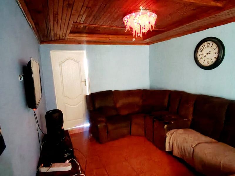 A living room featuring a timber-paneled ceiling and tiled flooring, providing a rustic foundation for potential interior updates.