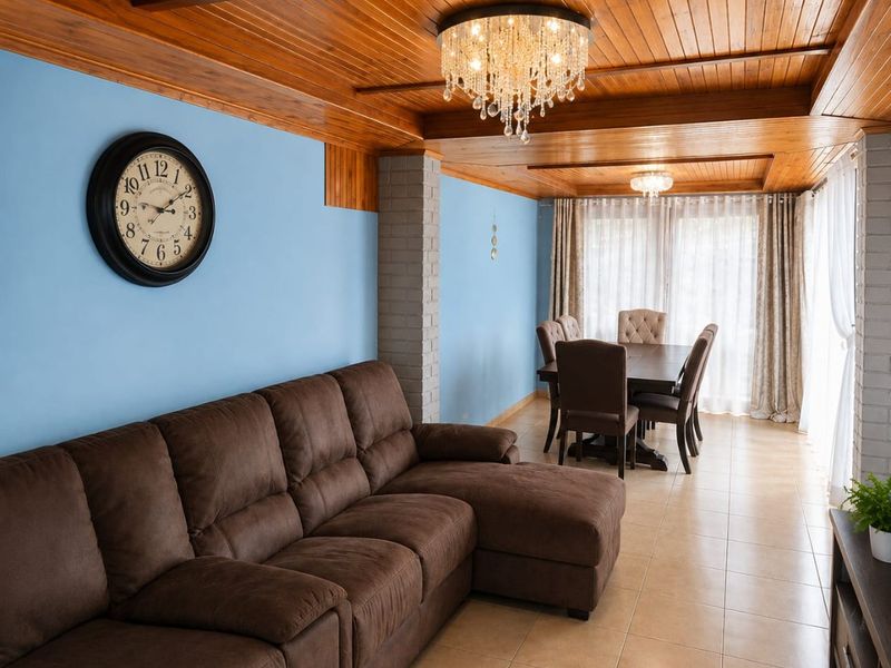 Open-plan living and dining area featuring a warm timber-clad ceiling, exposed brick accents, and elegant crystal chandeliers, creating a cozy and inviting atmosphere.