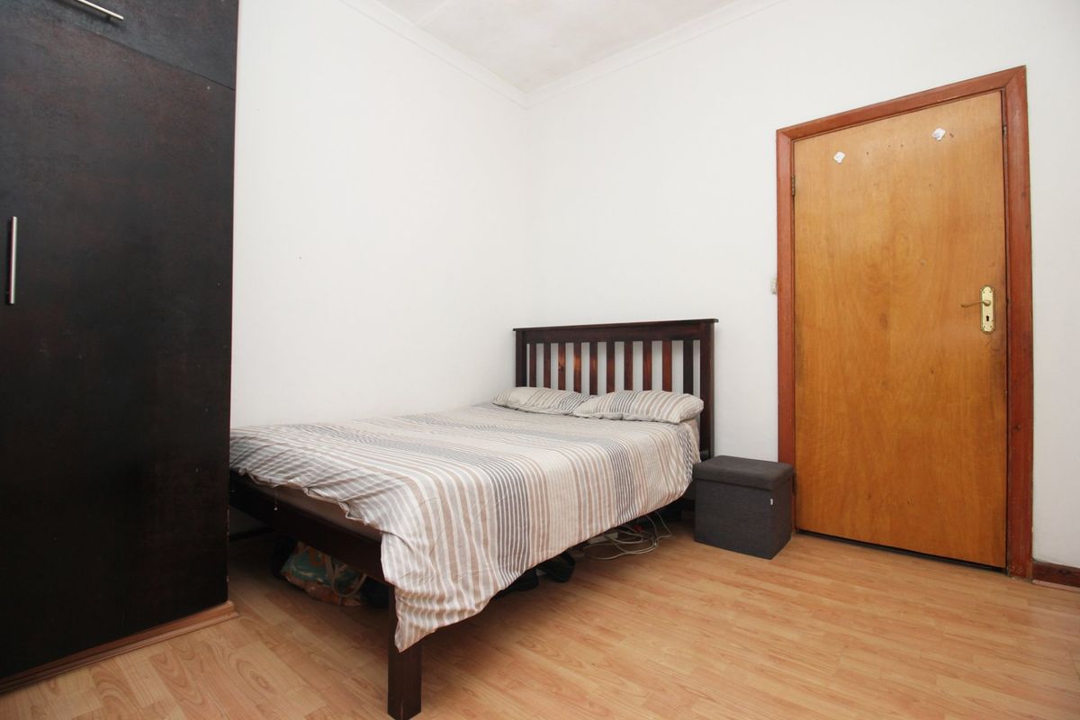 A functional bedroom featuring laminate flooring and a built-in wardrobe, offering a neutral space ready for personalization.