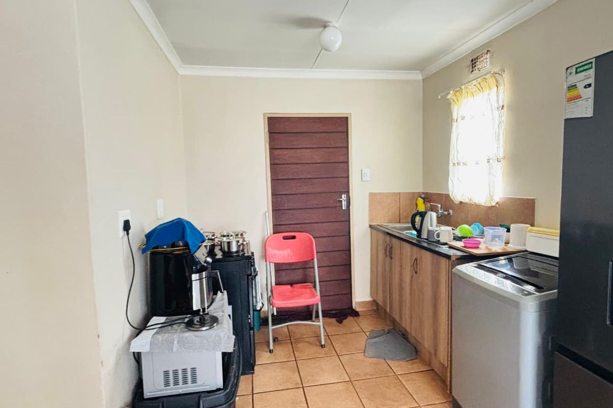 A functional kitchen area featuring laminate cabinetry, a stainless steel sink, and tiled flooring, providing a practical space for food preparation and utility tasks.