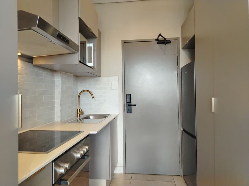Compact modern kitchen featuring sleek cabinetry, stone countertops, subway tile backsplash, and integrated stainless steel appliances.
