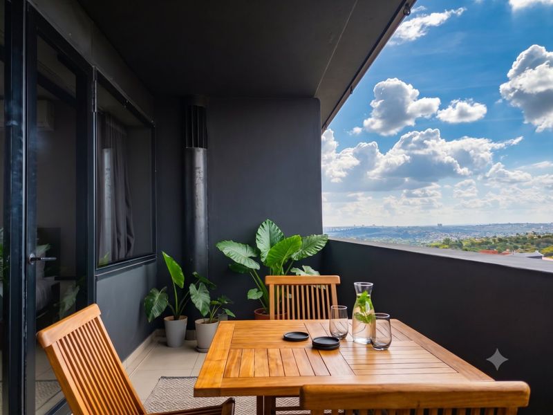 A modern, covered balcony featuring dark charcoal walls, tiled flooring, and expansive views of the surrounding landscape.