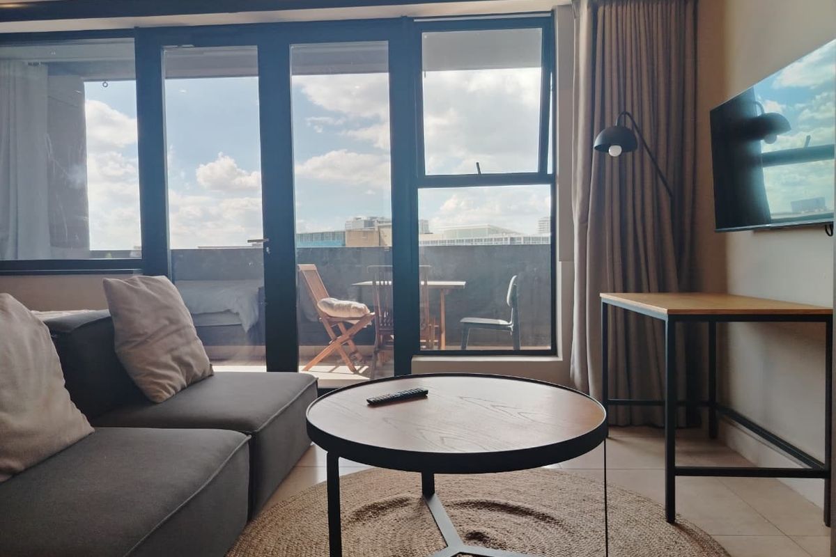 Modern living room featuring large sliding glass doors that open onto a balcony, providing ample natural light and a seamless indoor-outdoor flow.