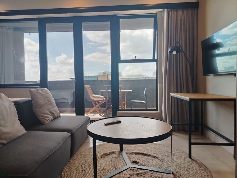 Modern living room featuring large sliding glass doors that open onto a balcony, providing ample natural light and a seamless indoor-outdoor flow.