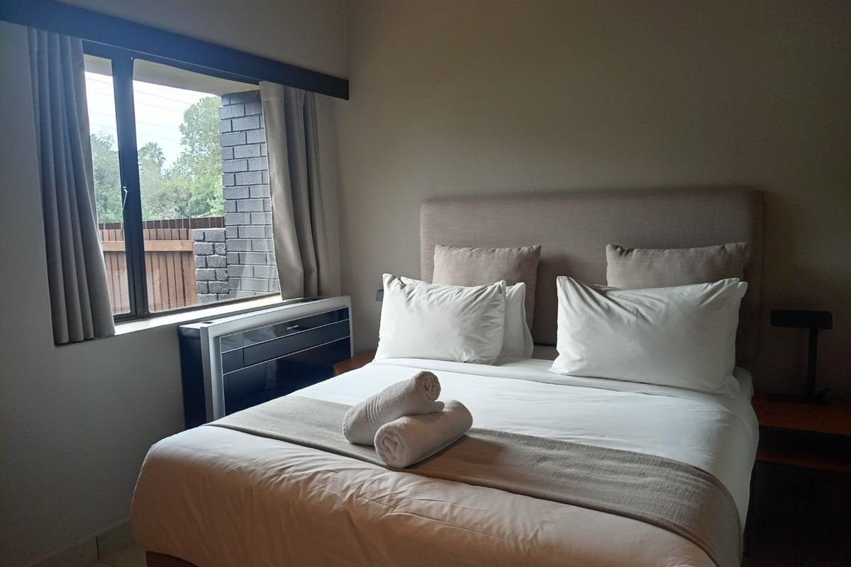 A well-maintained bedroom featuring tiled flooring and a built-in air conditioning unit positioned beneath the window.