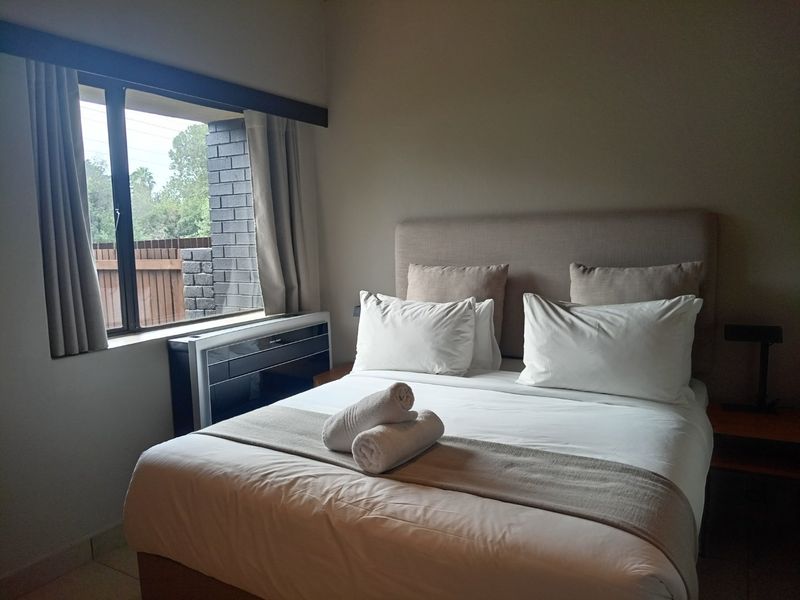 A well-maintained bedroom featuring tiled flooring and a built-in air conditioning unit positioned beneath the window.