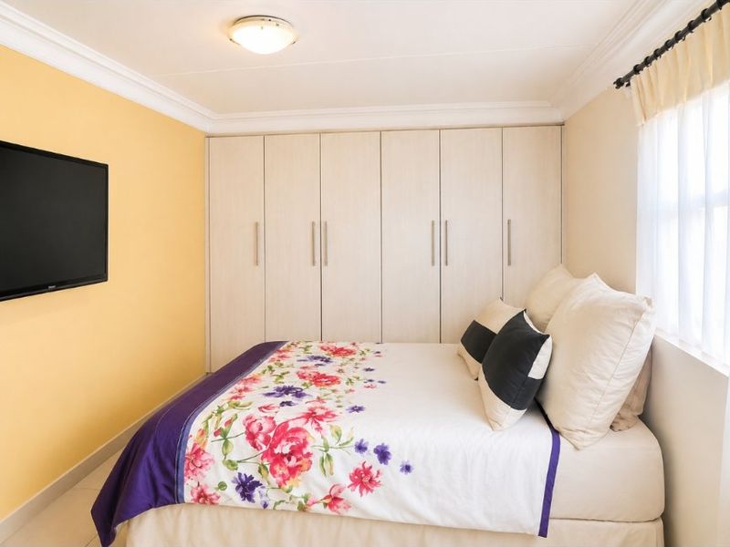 A well-maintained bedroom featuring floor-to-ceiling built-in cupboards, decorative ceiling cornicing, and neutral wall finishes.