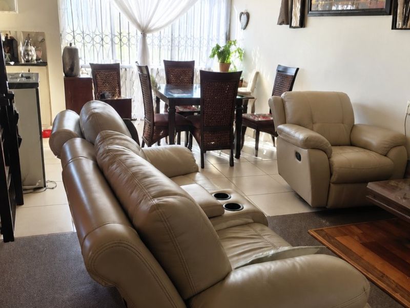 Open plan living and dining area featuring a combination of tiled and carpeted flooring with natural light from the window.