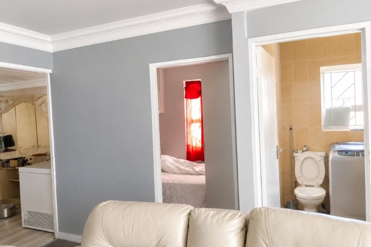 Living area featuring crown molding with views into an adjacent bedroom and a tiled bathroom containing a toilet.