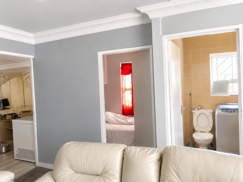 Living area featuring crown molding with views into an adjacent bedroom and a tiled bathroom containing a toilet.