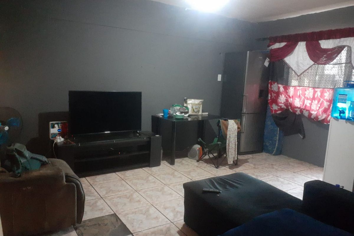 Open plan living area featuring ceramic floor tiles and dark painted walls, offering a functional space for lounge and dining arrangements.