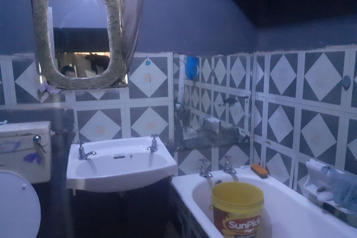 A dated bathroom featuring a pedestal basin, bathtub, and toilet with patterned wall tiles, requiring significant renovation and modernization.
