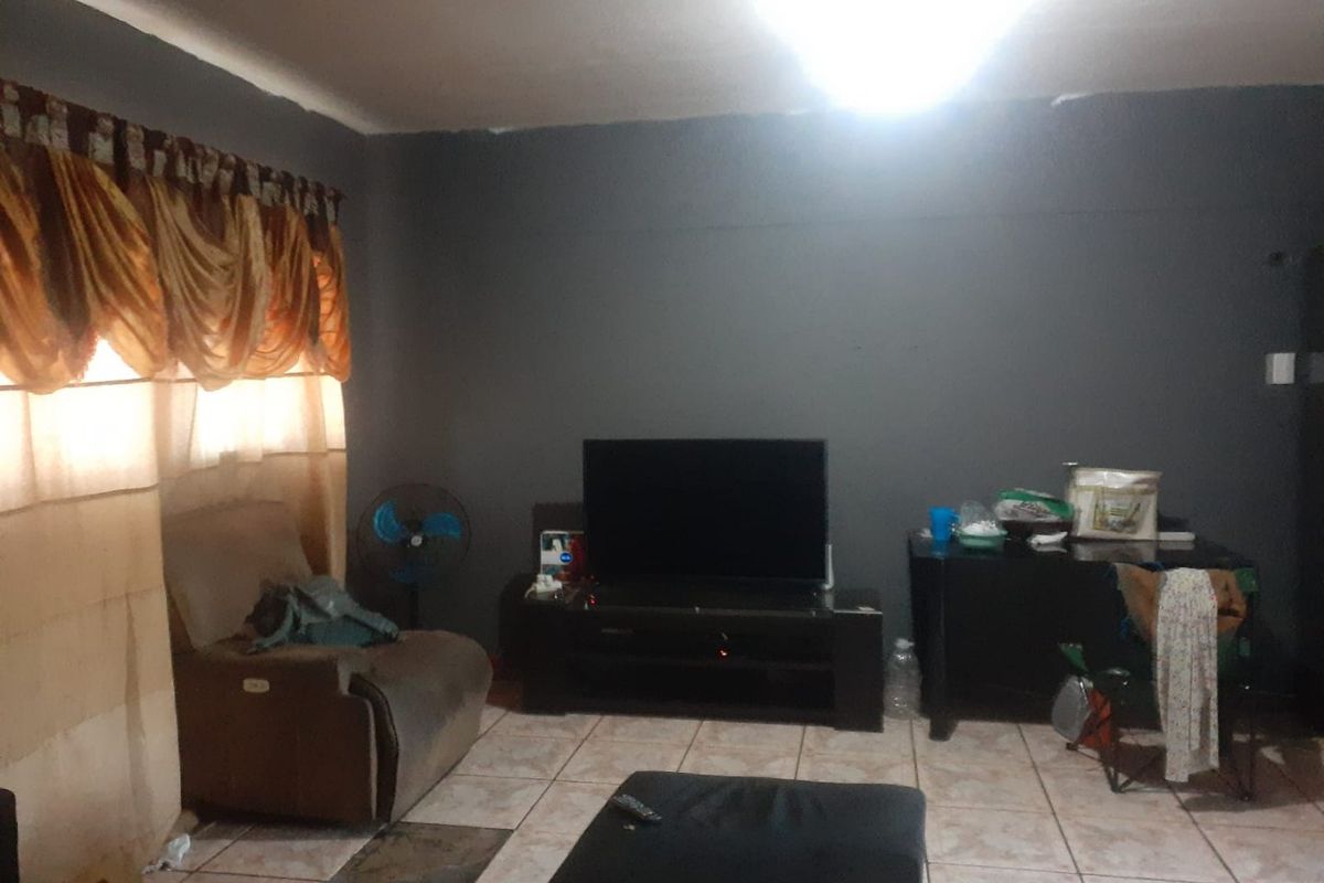 A living room area featuring tiled flooring and dark grey painted walls, providing a blank canvas for potential interior updates.