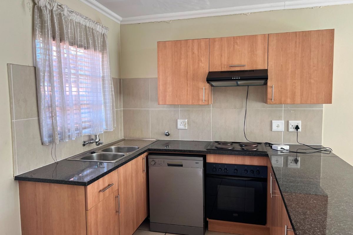 Functional kitchen featuring laminate cabinetry, granite countertops, built-in oven, electric hob, extractor fan, and a double basin sink with tiled backsplash.