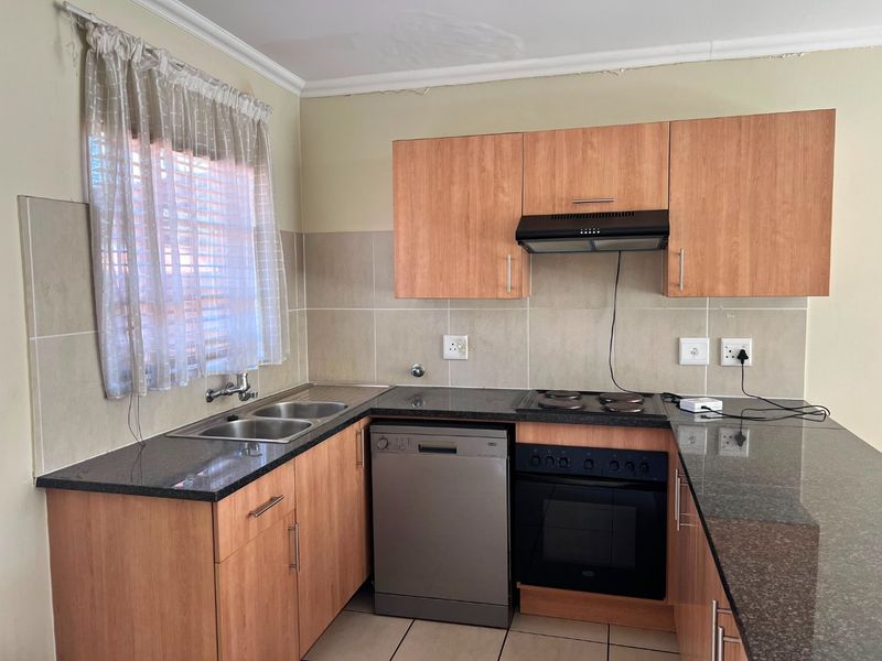Functional kitchen featuring laminate cabinetry, granite countertops, built-in oven, electric hob, extractor fan, and a double basin sink with tiled backsplash.