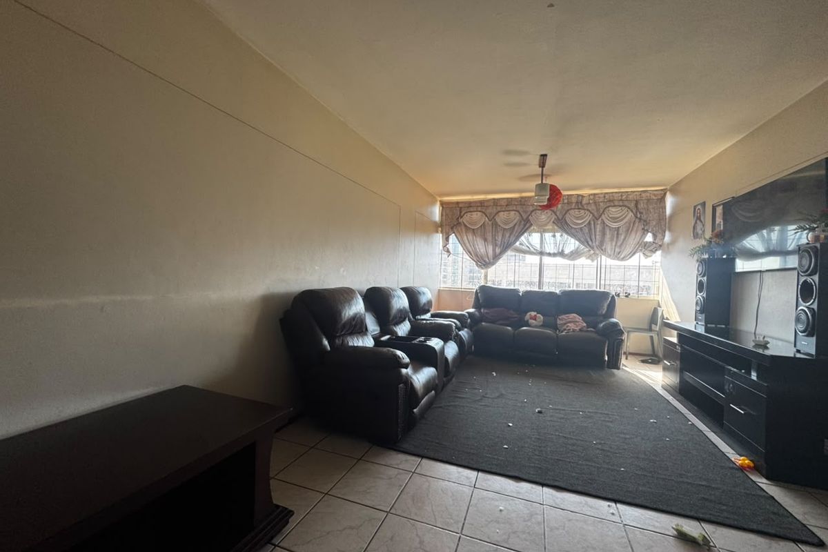 A living room featuring tiled flooring and a ceiling fan, requiring cosmetic updates to the walls and ceiling to enhance the space.
