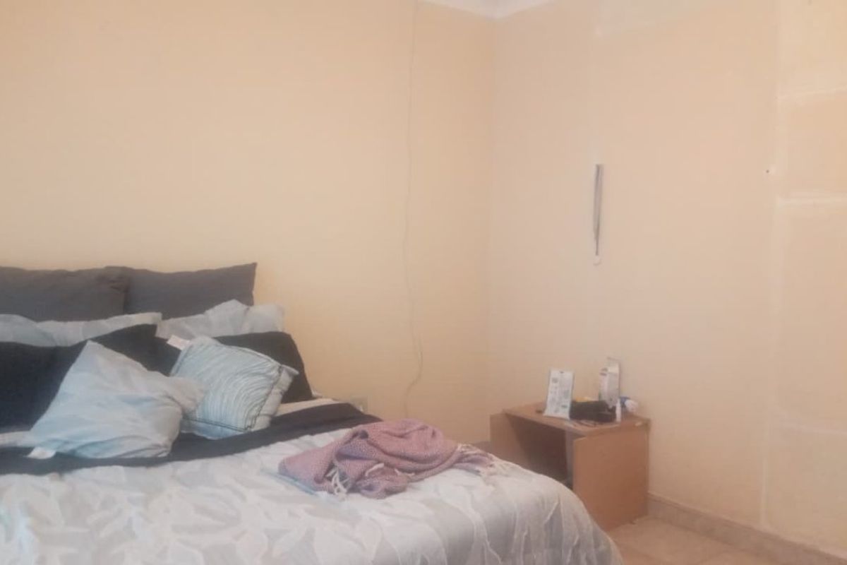 A bedroom featuring plain walls with visible patching and uneven finishes, requiring cosmetic attention to improve the overall aesthetic.