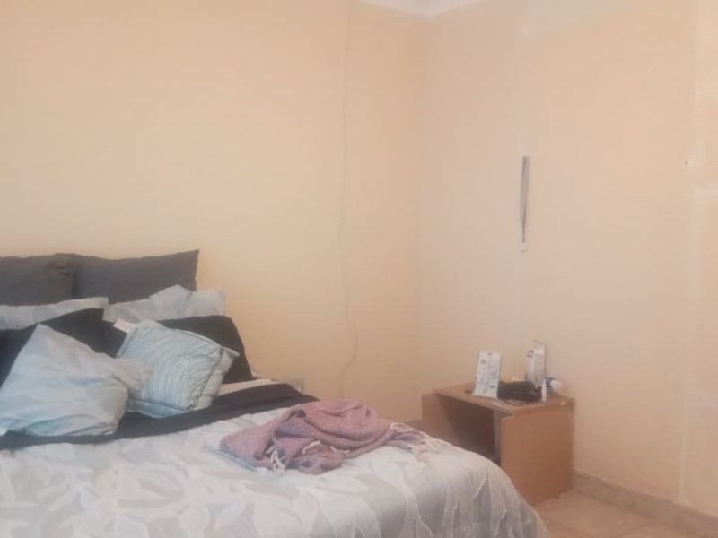 A bedroom featuring plain walls with visible patching and uneven finishes, requiring cosmetic attention to improve the overall aesthetic.