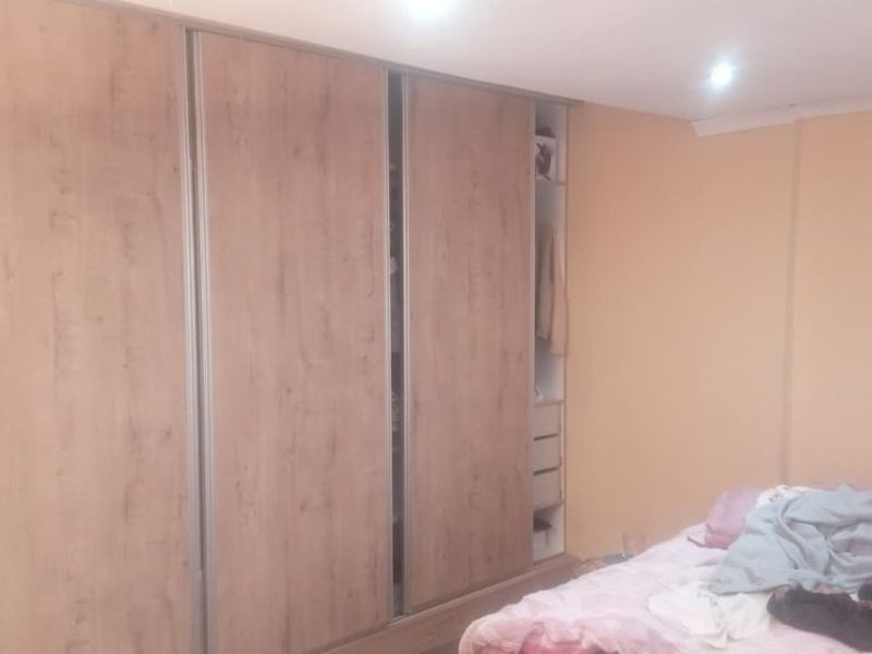 A bedroom featuring a large, wood-finish built-in wardrobe with sliding doors and integrated shelving.