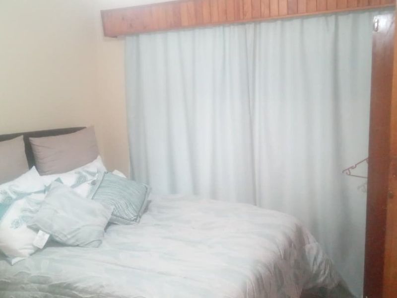 A bedroom featuring a built-in wardrobe and a wooden pelmet above the window area.