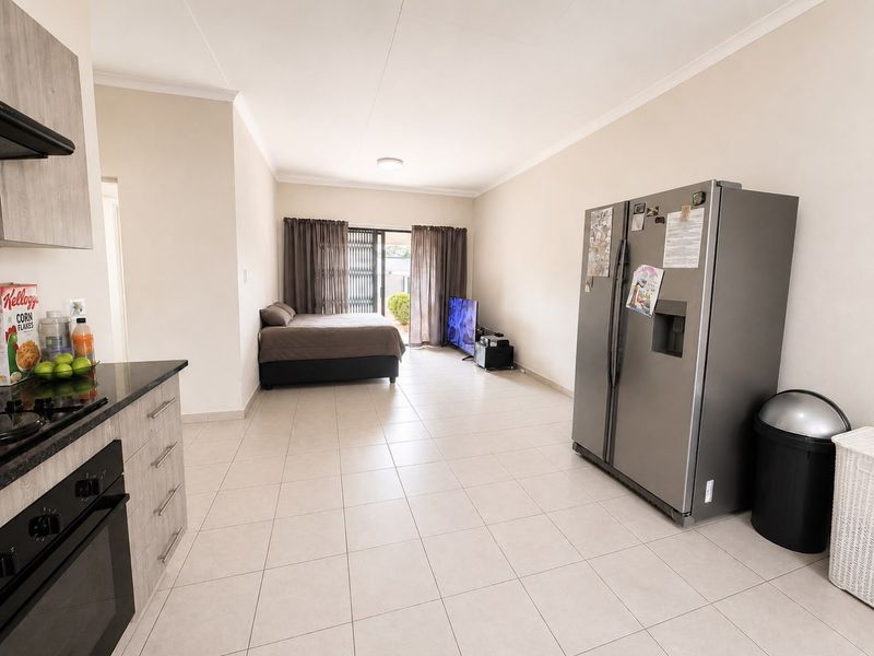 Open-plan living area featuring tiled flooring, a compact kitchen with built-in appliances, and sliding door access to the exterior.