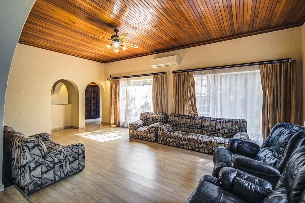 Spacious living room featuring a warm timber-clad ceiling, ceiling fan, split-system air conditioning, and arched architectural details with laminate flooring throughout.