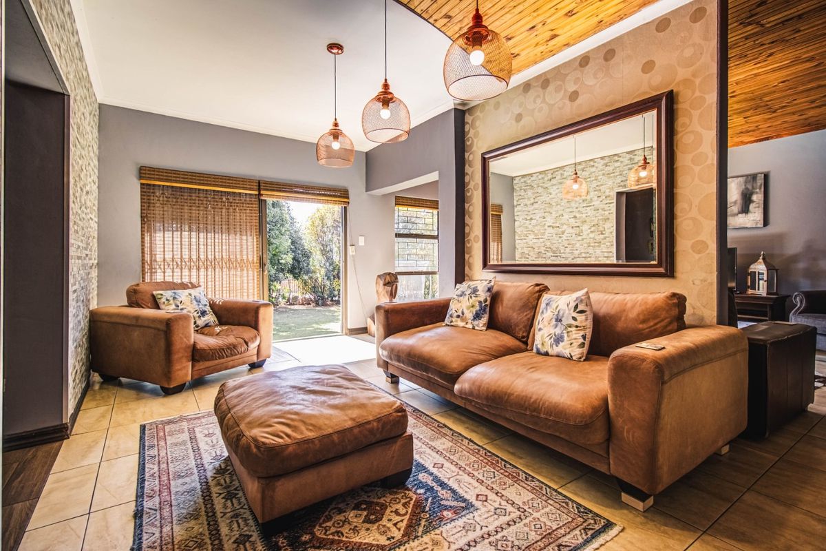 A well-maintained living room featuring tiled floors, a warm timber ceiling, and a sliding door providing direct access to the garden.