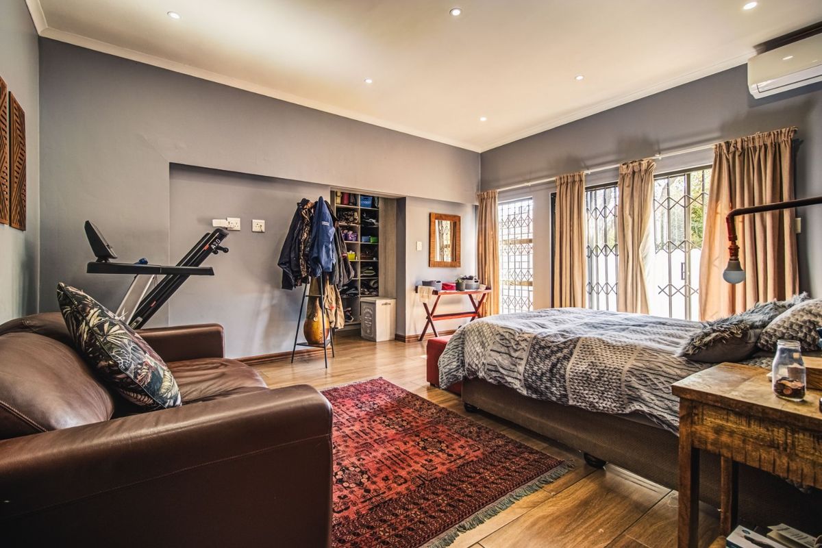 Spacious bedroom featuring laminate flooring, recessed lighting, built-in shelving, and direct access to the exterior through security-gated glass doors.