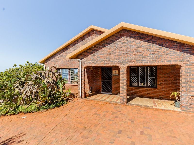 A well-maintained face brick house featuring a paved driveway, covered entrance porch, and secure window treatments.