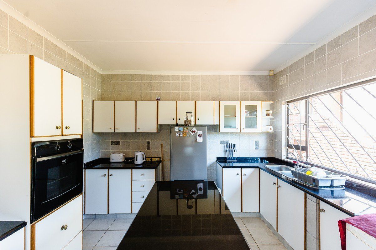 Functional kitchen featuring granite countertops, tiled backsplash, built-in oven, and ample cabinetry with a central island workspace.