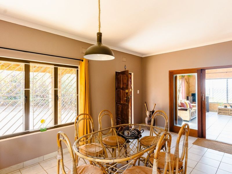 A dining room featuring tiled flooring, a pendant light, and access to an adjacent patio through a sliding glass door.