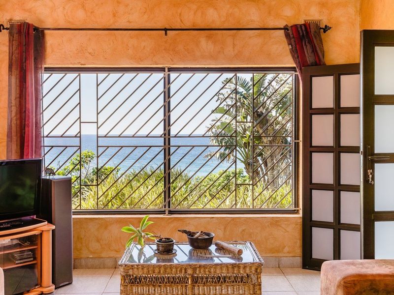 Living room featuring textured walls, tiled flooring, and a large window with security bars offering a direct ocean view.