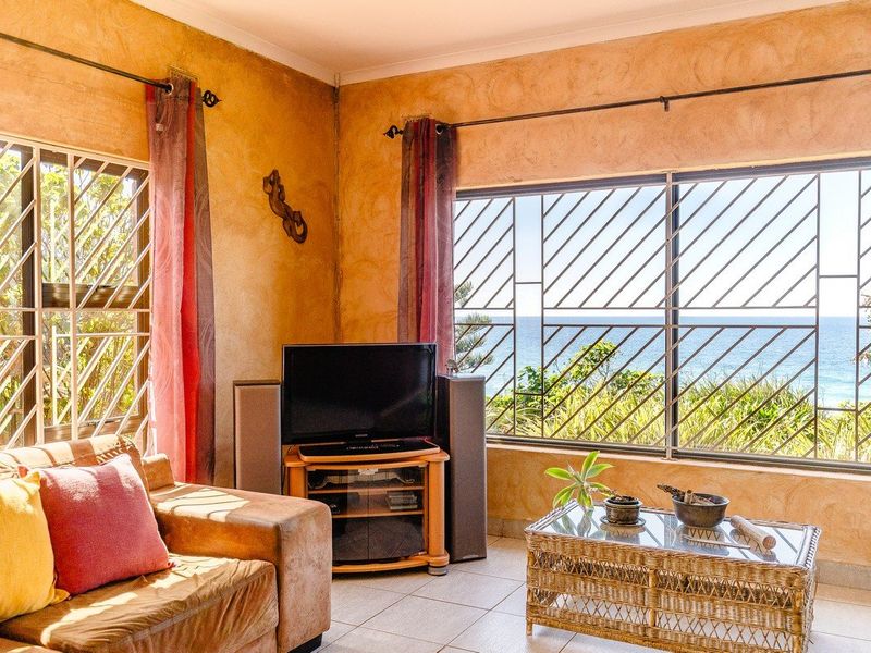 Living room featuring textured walls, tiled flooring, and large windows with security bars offering an ocean view.