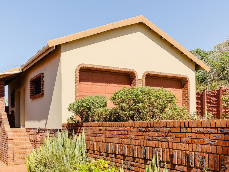 A detached double garage featuring brick detailing, a tiled roof, and an external brick staircase, set behind a low brick boundary wall.