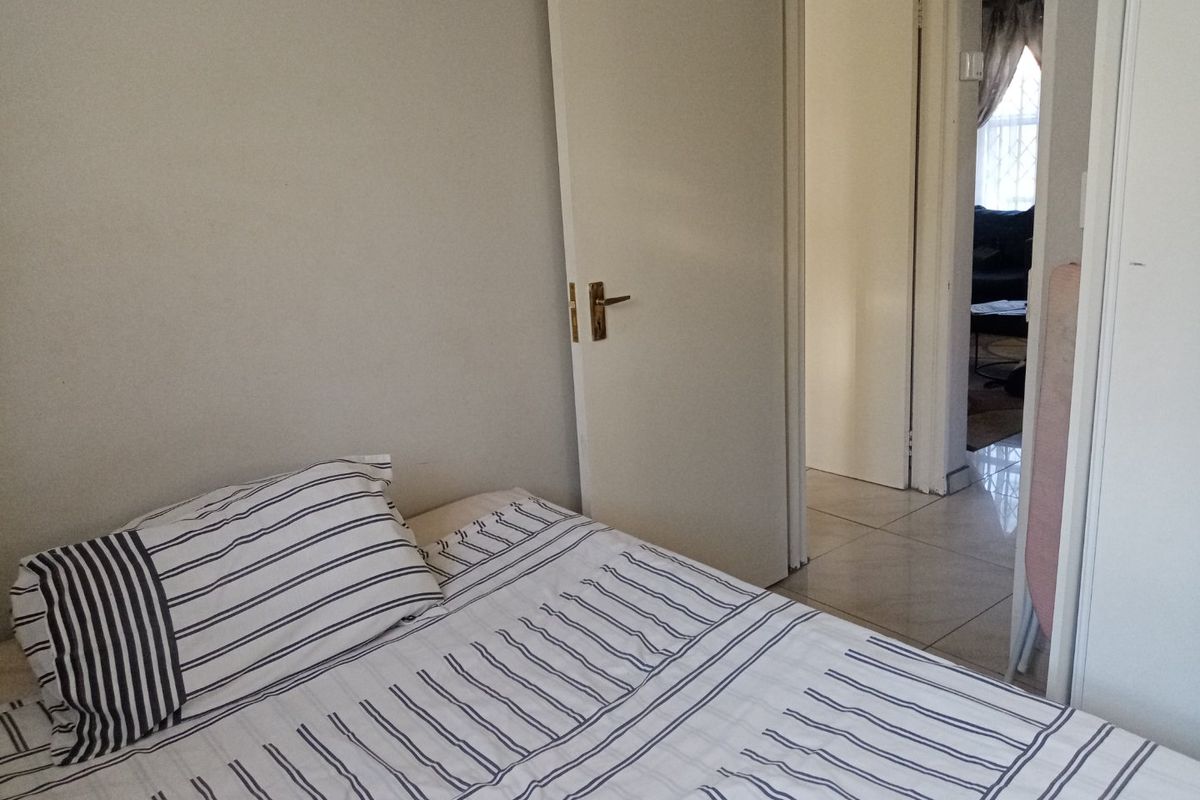 A standard bedroom featuring tiled flooring and an internal door, providing access to the adjacent living area.