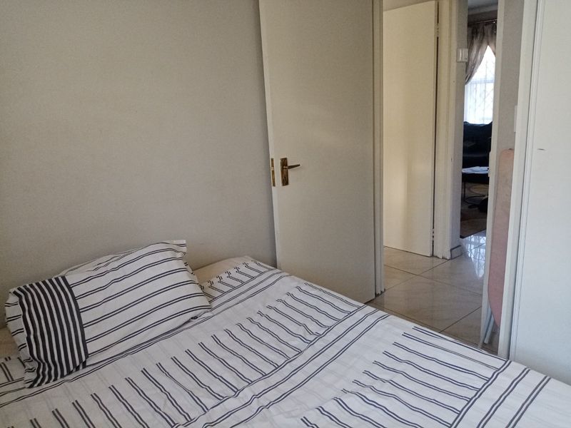 A standard bedroom featuring tiled flooring and an internal door, providing access to the adjacent living area.
