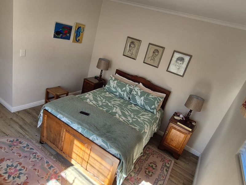 A well-maintained bedroom featuring laminate flooring, window shutters, and an integrated air conditioning unit.