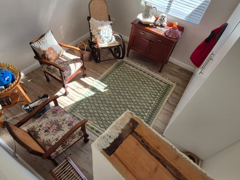 A bedroom space featuring laminate flooring, built-in storage, and natural light through venetian blinds, viewed from an elevated position.