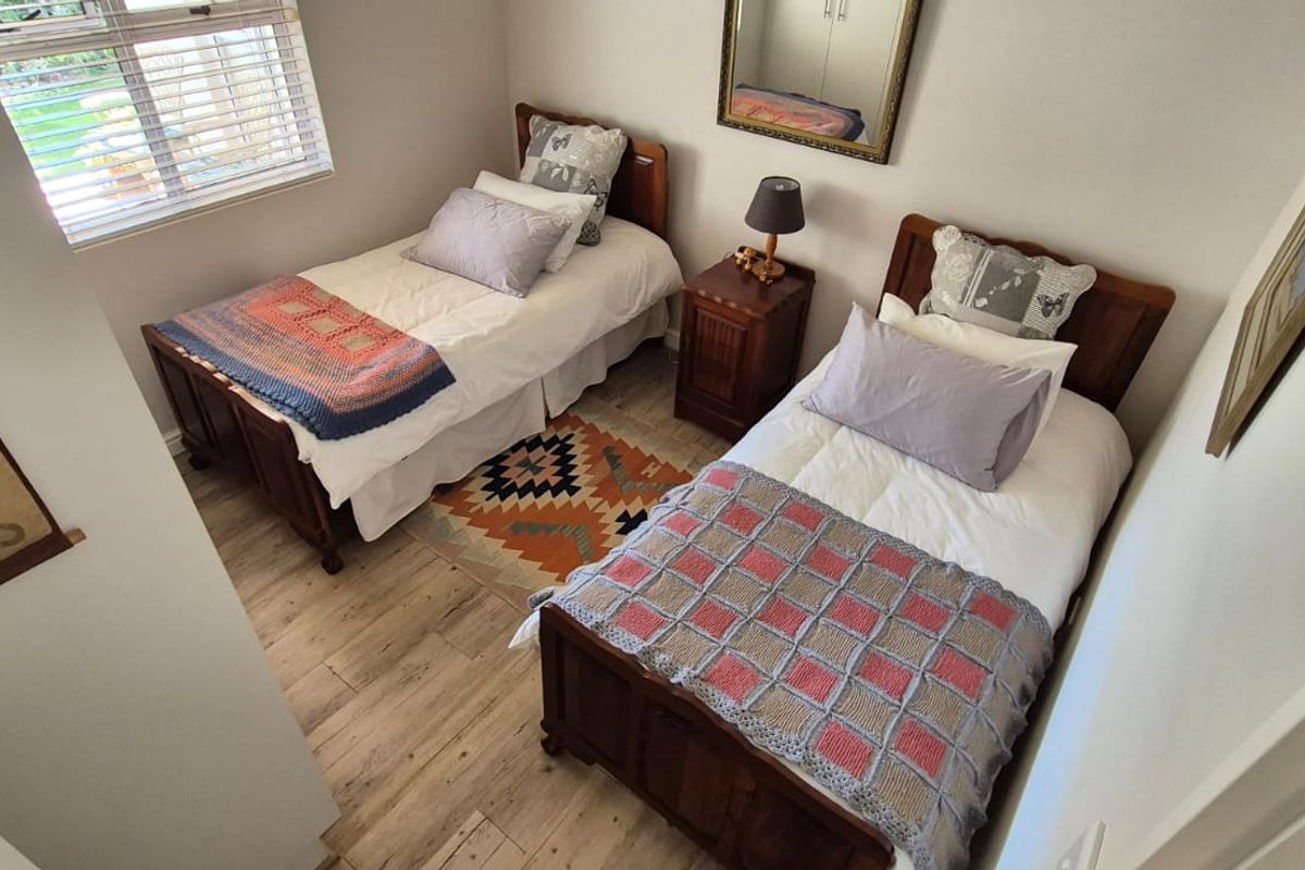 A well-maintained bedroom featuring light-toned laminate flooring, a built-in cupboard, and a window providing natural light.