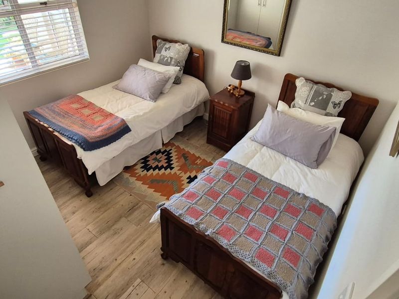 A well-maintained bedroom featuring light-toned laminate flooring, a built-in cupboard, and a window providing natural light.