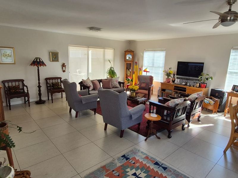 Spacious open-plan living and dining area featuring neutral tiled flooring, ceiling fan, and large windows with venetian blinds allowing for ample natural light.