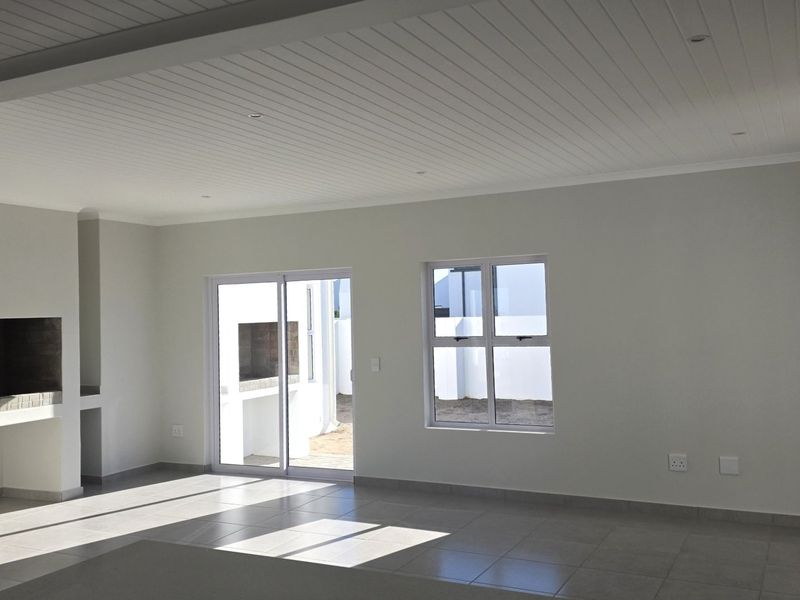 Spacious open-plan living area featuring tiled floors, a built-in fireplace, and sliding glass doors leading to an outdoor space.