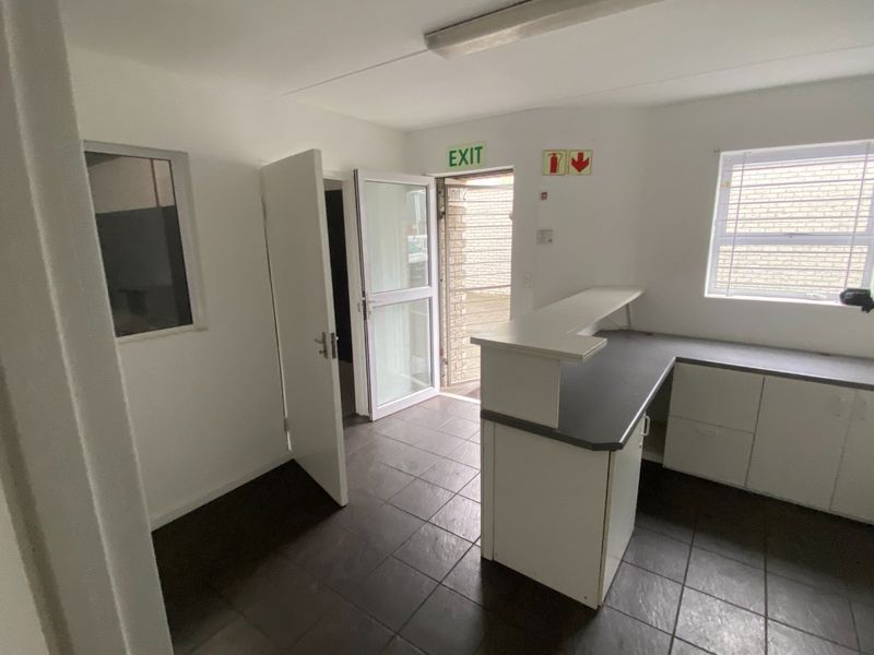 A functional office space featuring a built-in reception counter, tiled flooring, and natural light from windows, suitable for a professional workspace.