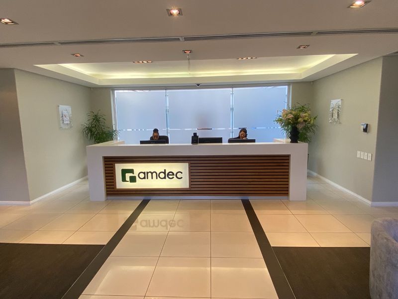 Professional commercial reception area featuring a modern built-in desk, recessed lighting, and polished tiled flooring.