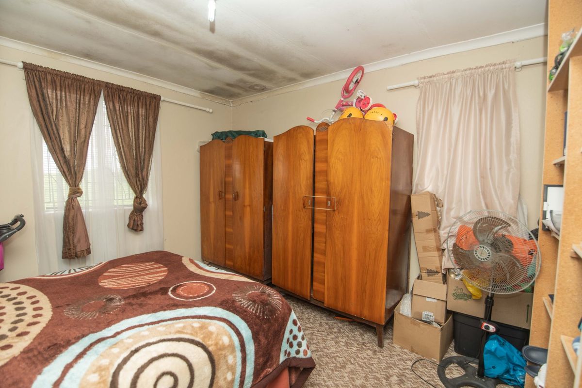 A bedroom featuring visible ceiling water damage and staining, requiring maintenance and repair to the ceiling finish.