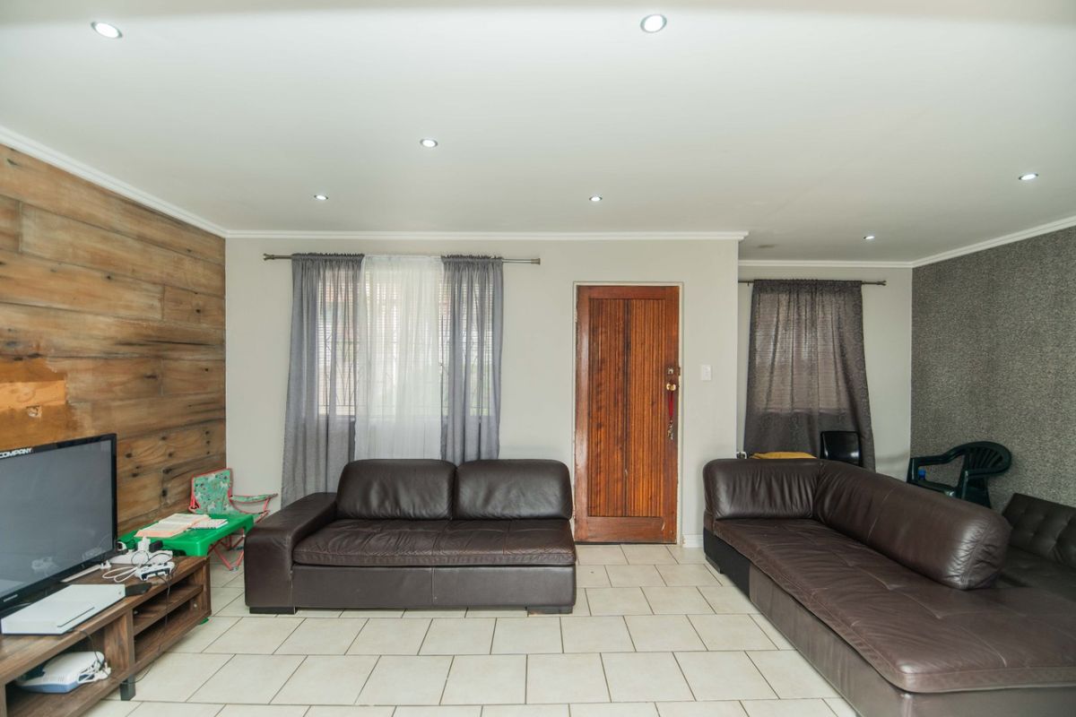 Spacious living room featuring tiled flooring, recessed downlights, and a combination of timber and textured feature walls.